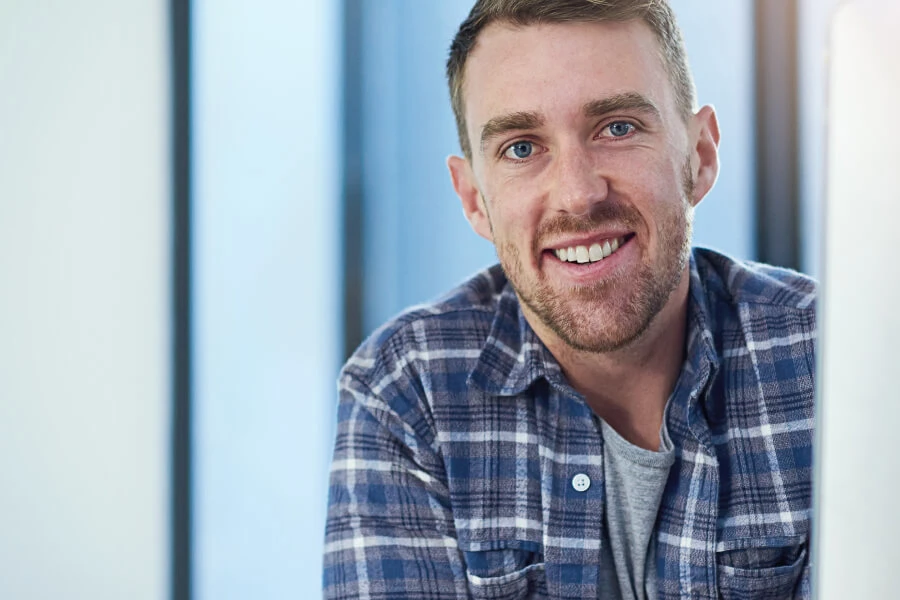 Coder in blue plaid shirt looking at camera