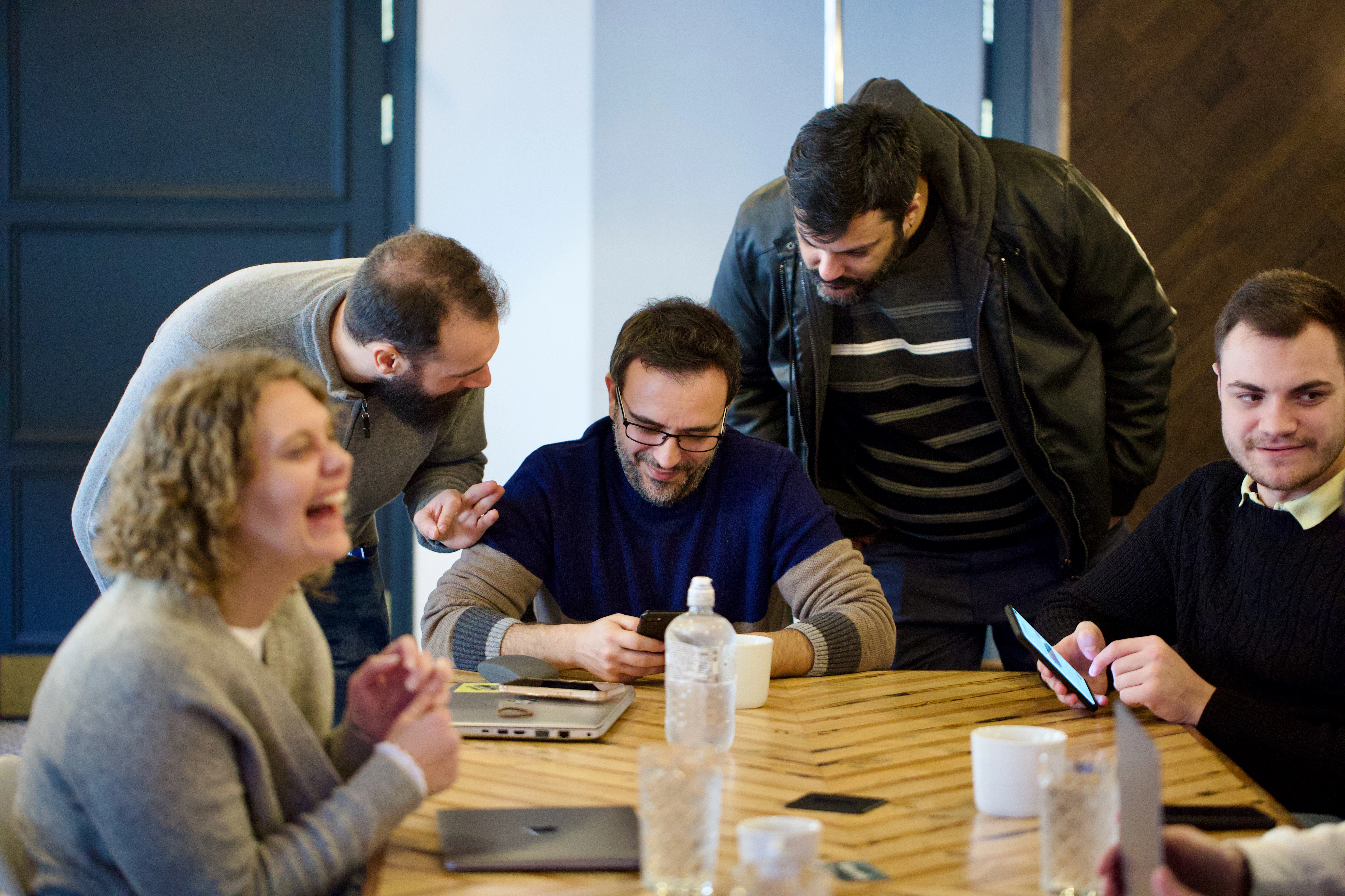 A picture of a group of people sat around a table haivng different conversations